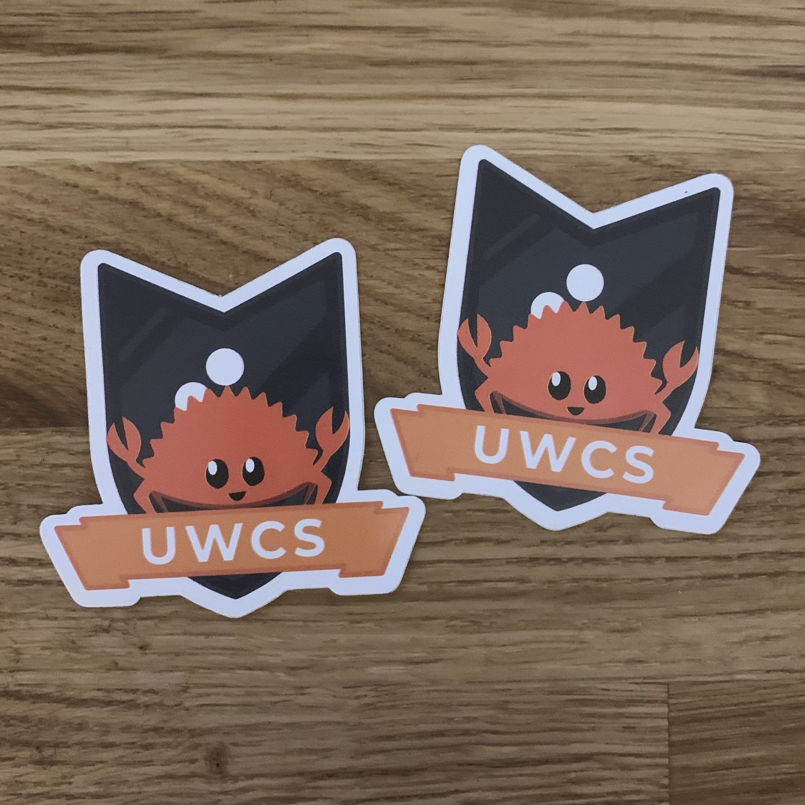 Stickers of the UWCS logo with Ferris the crab on them